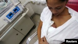 FILE - A mother performs Kangaroo care, or skin-to-skin contact, with her premature baby to give the baby the physical stimulation it needs.