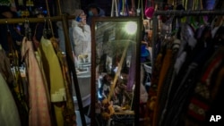 A mirror reflects women as they browse fashion accessories at a New Year bazaar in Beijing on Jan. 1, 2024. U.N. economists reported Thursday that they expect slow global growth this year but said they were optimistic about China's outlook.