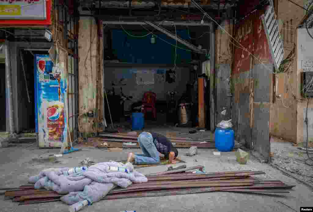 A man prays outside his shop damaged in an Israeli strike, after the ceasefire between Israel and Hezbollah, in Tyre, southern Lebanon. 