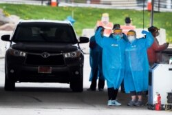 FILE - Medical workers flex their muscles as they pose for a photo at a drive-thru COVID-19 testing site in Waterloo, Iowa, May 1, 2020.