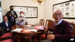 Syukuro Manabe, right, speaks to reporters at his home in Princeton, N.J., Tuesday, Oct. 5, 2021. (AP Photo/Seth Wenig)