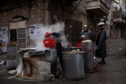 An ultra-Orthodox Jewish man dips cooking utensils in boiling water to remove remains of leaven in preparation for the upcoming Jewish holiday of Passover in Jerusalem, March 26, 2021.
