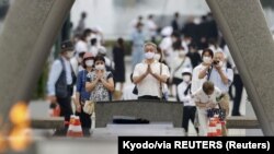 Warga mengenakan masker saat memberi penghormatan untuk para korban bom atom AS tahun 1945, di depan Cenotaph (tugu peringatan) Peace Memorial Park di Hiroshima, Jepang barat, pada peringatan 75 tahun bom atom di kota tersebut, 6 Agustus 2020. 
