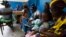 FILE - Women holding children wait for a medical examination at the health center in Gbangbegouine, Ivory Coast