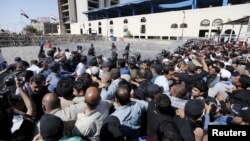 Supporters of prominent Iraqi Shi'ite cleric Muqtada al-Sadr try to remove a barbed wire fence as they break the checkpoint on the bridge leading to Baghdad's heavily fortified Green Zone in Iraq, March 18, 2016.