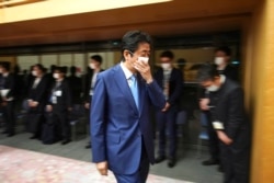 Perdana Menteri Jepang Shinzo Abe membetulkan letak masker wajahnya seusai menggelar konferensi pers di kantor perdana menteri di Tokyo, 4 Mei 2020.