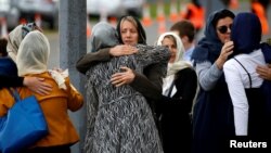 People embrace as they attend the burial ceremony of the victims of the mosque attacks, at the Memorial Park Cemetery in Christchurch, New Zealand, March 21, 2019.