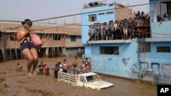A woman is pulled to safety in a zip line harness in Lima, Peru, March 17, 2017. Intense rains and mudslides over the previous fewer days have wrought havoc around the Andean nation and caught residents in Lima, a desert city of 10 million where it almost never rains, by surprise. 