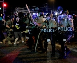A man is detained after a standoff between protesters and police Monday, Aug. 18, 2014, during a protest for Michael Brown, who was killed by a police officer Aug. 9 in Ferguson, Mo.