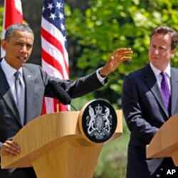 British Prime Minister David Cameron (R) watches U.S. President Barack Obama speak to reporters at Lancaster House in London May 25, 2011