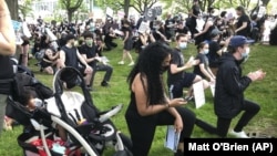 Anjel Newmann, 32, kneels while scanning her phone during a peaceful rally in Providence, R.I. on Friday, June 5. Newmann said she’s mostly using Instagram and Facebook to organize protests while people younger than her are using Snapchat. (AP Photo/Matt O'Brien)
