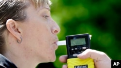 California Highway Patrol Sgt. Jaimi Kenyon blows into a breathalyzer held by Sacramento Police Corporal Luke Moseley during a demonstration of devices used to test drivers suspected of impaired driving Wednesday, May 10, 2017, in Sacramento, Calif. (AP)