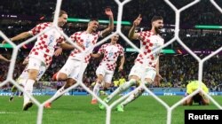 Josko Gvardiol dari Kroasia, Ante Budimir, Dejan Lovren, dan Lovro Majer merayakan kemenangan Kroasia ke semi final saat Marquinhos dari Brasil terlihat sedih setelah gagal mengeksekusi penalti dan tersingkir dari Piala Dunia. (Foto: REUTERS/Matthew Childs)