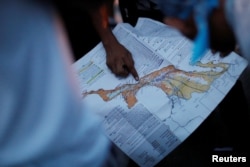FILE - A migrant, part of a caravan of thousands traveling from Central America en route to the United States, points at a map while rest in Santiago Niltepec, Mexico, Oct. 29, 2018.