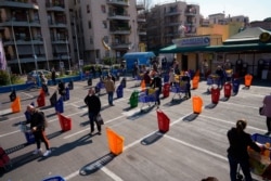 People stand apart as they line up to enter a supermarket in Rome on March 20, 2020.