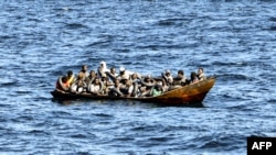Des migrants d'origine africaine tentant de fuir vers l'Europe à bord d'un petit bateau, en mer entre la Tunisie et l'Italie, le 10 août 2023. (Photo FETHI BELAID / AFP)