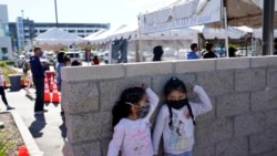 Dua orang anak perempuan tampak menunggu giliran untuk menjalani tes COVID-19 di salah satu lokasi tes di Kampus Kesehatan Martin Luther King Jr. di Los Angeles, pada 3 Januari 2022. (Foto: AP/Marcio Jose Sanchez)