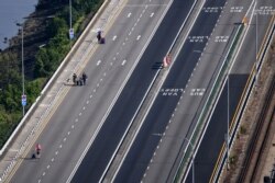 People walk across the causeway linking Malaysia's southern state of Johor (top) and Singapore, Apr. 1, 2020.