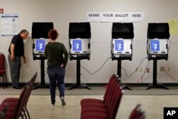 FILE - Kelly Monroe, investigator with the Georgia Secretary of State office, takes a look at a new voting machine that produces a paper record being tested at a polling site in Conyers, Ga., Oct. 19, 2017.