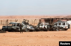 FILE - Algerian soldier stands near damaged cars used by Islamist militants during siege near the Tiguentourine Gas Plant, In Amenas, Jan. 31, 2013.