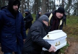 A Polish imam, right, and two other members of a Muslim community bury the tiny white casket of an unborn Iraqi boy, in Bohoniki, Poland, on Tuesday Nov. 23, 2021.