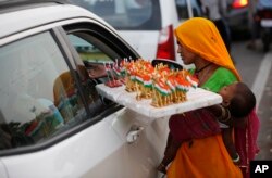 A woman sells Indian national flag memorabilia on the eve of Independence Day in Lucknow, India, Tuesday, Aug. 14, 2018.
