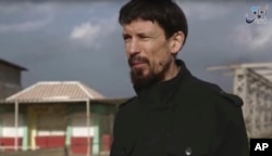 FILE - This still taken from video released Dec. 7, 2016, by the Islamic State's Amaq news agency, shows captive British photojournalist John Cantlie in what appeared to be central Mosul, Iraq.