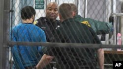 Esteban Santijago (u plavoj majici) u pratnji pripadnika policije posle hapšenja