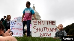 Mason Palmer (R), 10 months old, has his picture taken by his father in front of federal workers demonstrating for an end to the U.S. government shutdown on the west front of the U.S. Capitol in Washington, Oct. 13, 2013. 