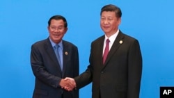 FILE: Cambodian Prime Minister Hun Sen, left, and Chinese President Xi Jinping, right, shake hands during the welcome ceremony for the Belt and Road Forum, at the International Conference Center at Yanqi Lake in Beijing, Monday, May 15, 2017. (Roman Pilipey/Pool Photo via AP)