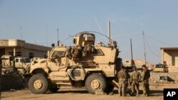 U.S. Army soldiers stand outside their armored vehicle on a joint base with Iraqi army south of Mosul, Iraq, Feb. 23, 2017.