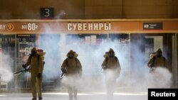 Russia's Emergencies Ministry members wearing personal protective equipment (PPE) spray disinfectant near a gift kiosk while sanitizing the Kievsky Railway Station amid the outbreak of the coronavirus disease (COVID-19) in Moscow, Russia May 18, 2020. 