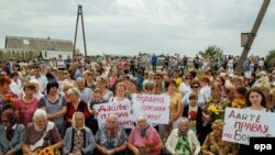 People gather at a monument to the victims of flight MH17 near its crash site, Hrabove, Ukraine, July 17, 2017.
