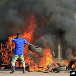 Wani matashi yana jefa taya cikinw uta a bayan da magoya bayan Alassane Ouattara suka fara zanga-zangar nuna kyamar kwace masa nasarar da suka ce ake kokarin yi