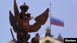 A sculpture of a double-headed eagle, a national symbol of Russia, is seen in front of a Russian national flag flying at half-mast on the roof of the State Hermitage Museum in St. Petersburg.