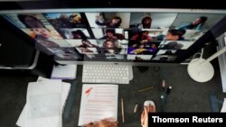 FILE - A student takes classes online with his companions using the Zoom app at home.