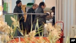 An unidentified person right, is followed by Algerian officials as they enter a morgue in Ain Amenas Algeria Monday, Jan. 21, 2013, where the bodies of the persons killed during the hostage situation at the gas plant in Ain Amenas,. At least 81 people ha