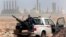 FILE - In this March 5, 2011 file photo, an anti-government rebel sits with an anti-aircraft weapon in front an oil refinery, after the capture of the oil town of Ras Lanouf, eastern Libya. The official Libyan news agency said Sunday, April 6, 2014 that t