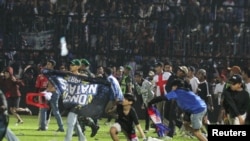 Suporter Arema FC memasuki lapangan setelah tim yang mereka dukung kalah dari Persebaya usai pertandingan liga BRI Liga 1 di Stadion Kanjuruhan, Malang, Provinsi Jawa Timur, 2 Oktober 2022. (Antara Foto/Ari Bowo Sucipto/via REUTERS)