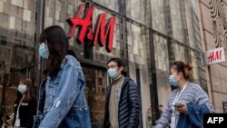 People walk past a store of Swedish clothing giant H&M in Beijing on March 25, 2021.