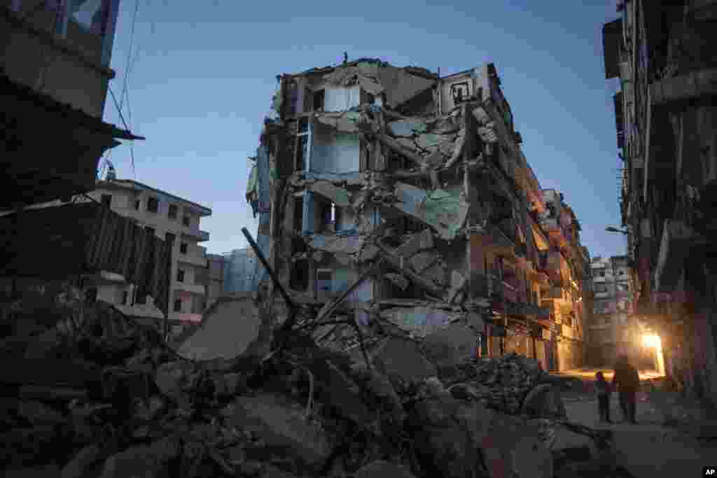 Residents walk past buildings damaged in heavy fighting between Free Syrian Army fighters and government forces in Aleppo, Syria, December 2, 2012. 