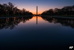 在华盛顿国家大草坪上，黎明之前，华盛顿纪念碑和绿树的影子投射在映影池（2016年4月17日）。