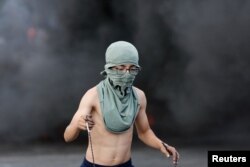 A Palestinian child holds a sling during clashes with Israeli forces near Ramallah in the Israeli-occupied West Bank on Oct. 18, 2023.