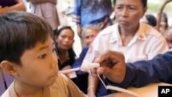 A U.S sailor gives a medical treatment to a Cambodian boy at a Buddhist pagoda, outside of Sihanoukville city, file photo. 