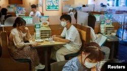 People sit in a restaurant using plexiglass separators to protect customers from coronavirus (COVID-19) disease in the Shibuya area of Tokyo, Japan, July 29, 2021.