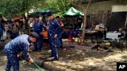 Pasukan keamanan Irak membersihkan lokasi pemboman bunuh diri di distrik Kadhimiyah, Baghdad, Irak hari Minggu (24/7). 