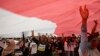 People wear T-shirts that read "Replace the President in 2019" stand under a large national flag during a rally in Jakarta, Indonesia, May 6, 2018. 