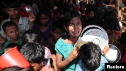A Rohingya refugee girl cries as children push each other while standing in the queue to collect food in the Palongkhali makeshift refugee camp in Cox's Bazar, Bangladesh, Nov. 7, 2017.