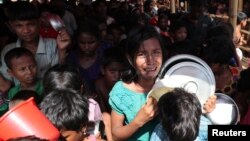 A Rohingya refugee girl cries as children push each other while standing in line to collect food in the Palongkhali makeshift refugee camp in Cox's Bazar, Bangladesh, Nov. 7, 2017.