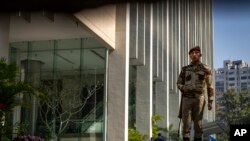 FILE - An armed security person stands guard at the gate of a building housing BBC office in New Delhi, India, on Feb. 15, 2023. Indian police raided the offices of a news website and homes of journalists, in what critics described as an attack on an independent news outlet.